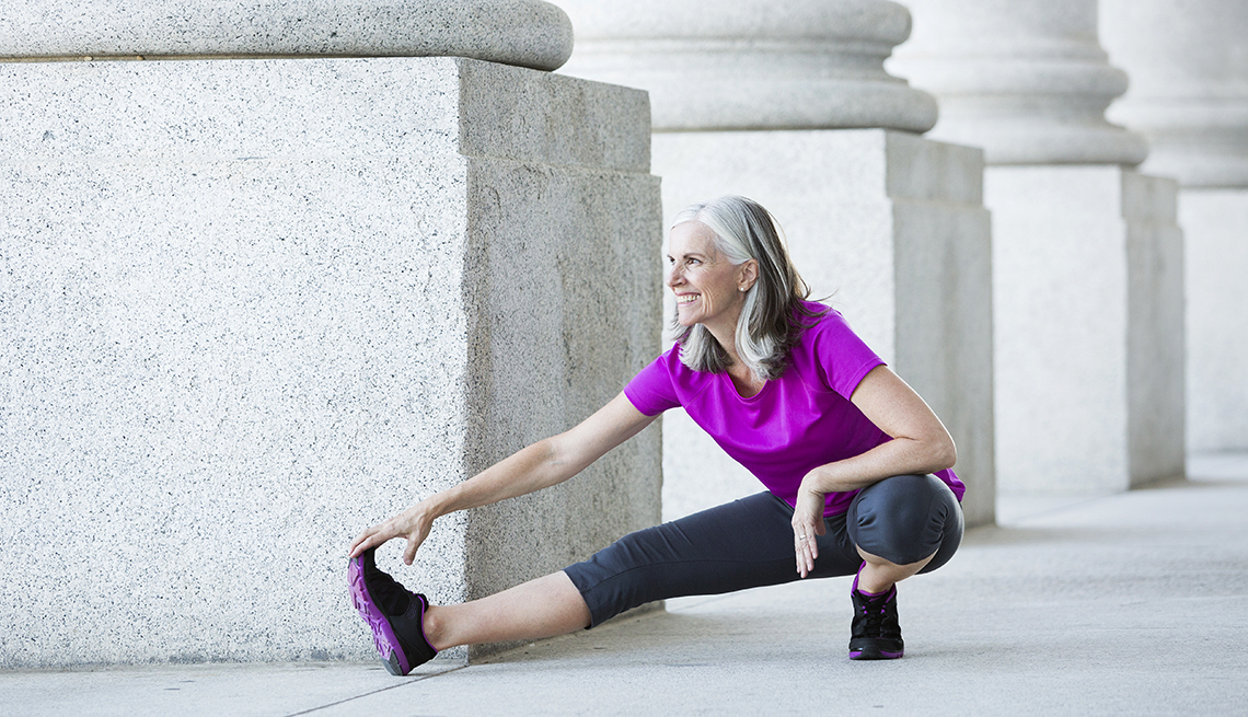 woman in exercise clothes stretching outside near large pillars