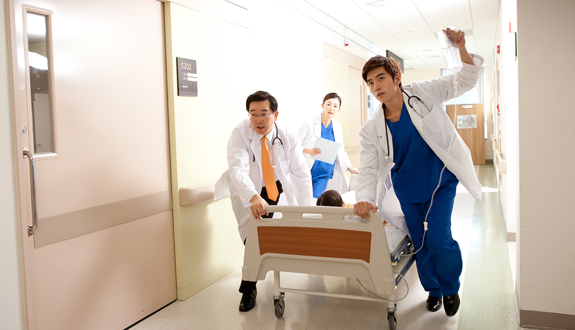 Three doctors rushing a patient on a gurney through the hospital.