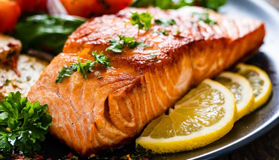 Cooked salmon on a plate with lemon slices and vegetables