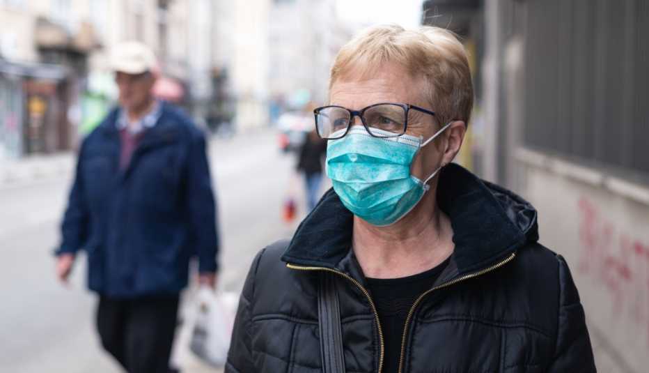 woman on the street wearing mask looking wary of other pedestrians