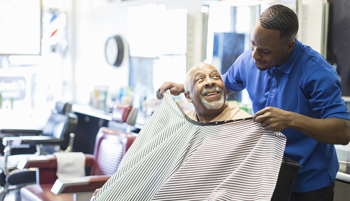 barber tying apron on customer in retro barbershop