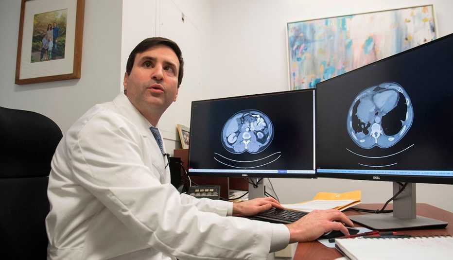 Dr. Christian Hinrichs, an investigator at the National Cancer Institute, shows a patient's CT scans, one with visible cancer (R) and the other showing a clean scan after treatment (L), as he speaks about his research in immunotherapy for HPV+ cancers, in