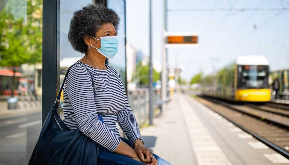 woman on train platform wearing a medical mask