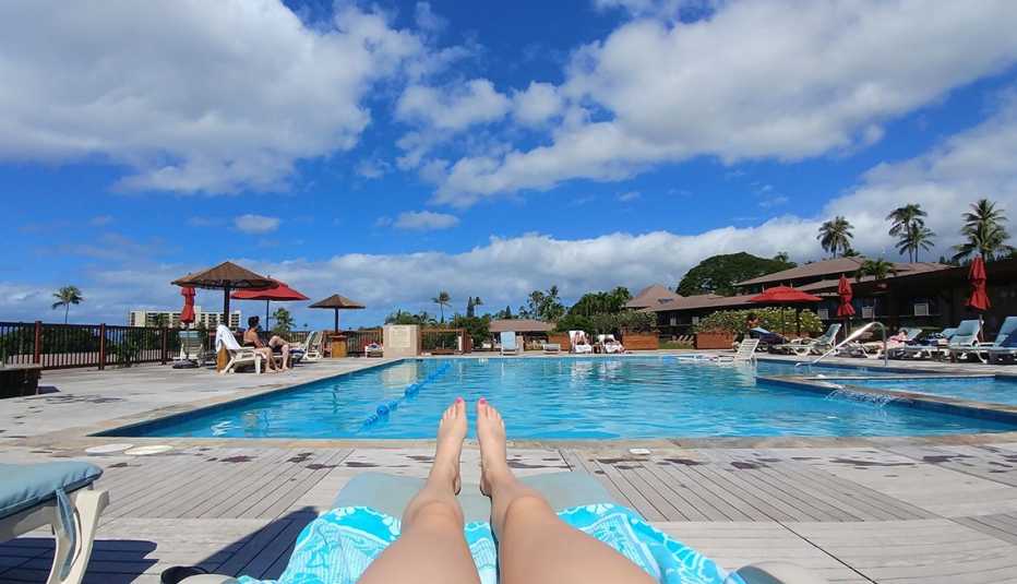wide view of a public pool from a lounge chair with a womans legs in foreground