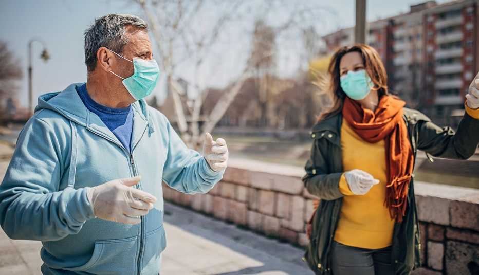 Man and woman walking outdoors wearing face masks.
