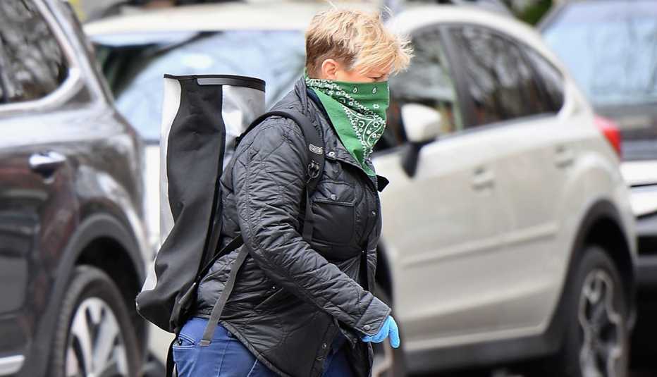 Woman walking through a parking lot wearing a green bandana as a face mask