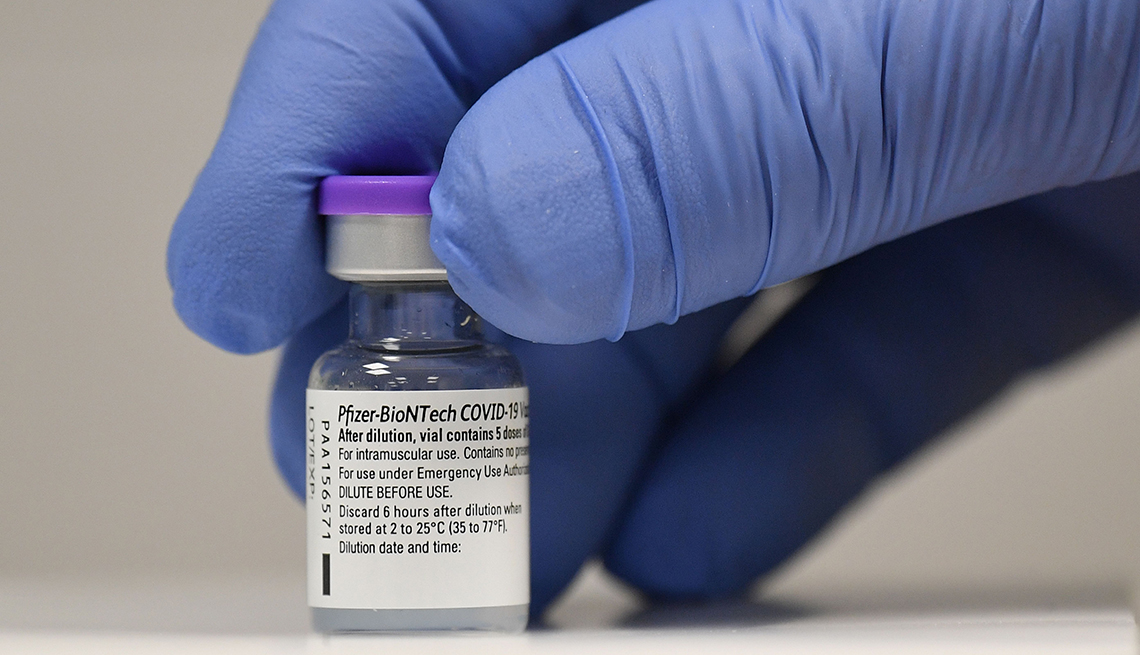a gloved hand holds a vial of Pfizer-BioNTech Covid-19 vaccine 