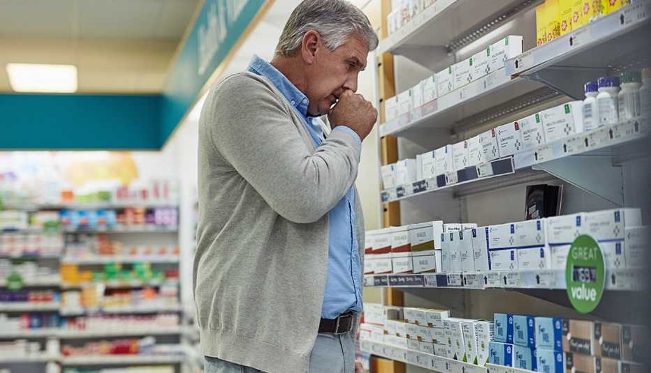 Shot of a mature man browsing the shelves of a pharmacy and coughing