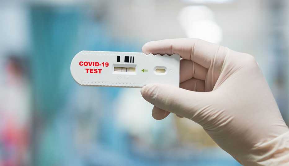 gloved hand holding positive Coronavirus rapid test