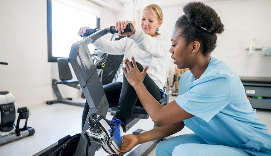An occupational therapist helping a female patient use a static bicycle during physical therapy
