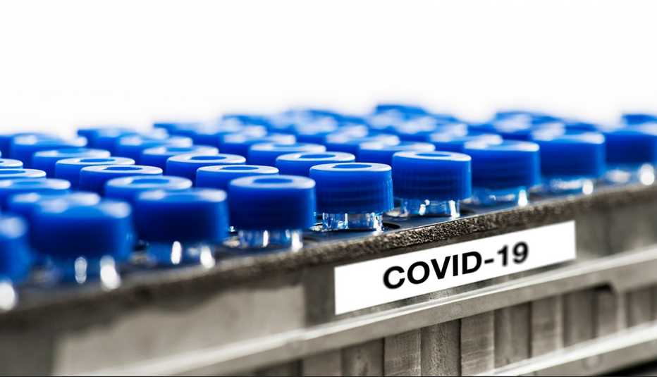Mini glass test tubes in metal rack with a label that says C O V I D - 19