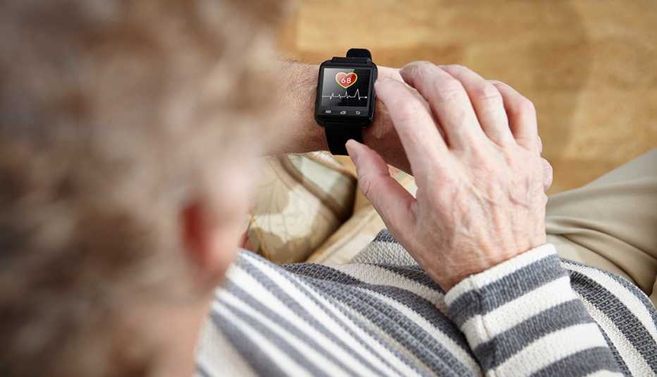 Older adult sitting in armchair using smartwatch