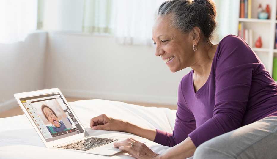 Woman sitting on her bed with a laptop video chatting with her grand child