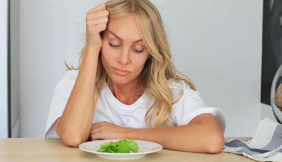 woman looking at salad not wanting to eat it