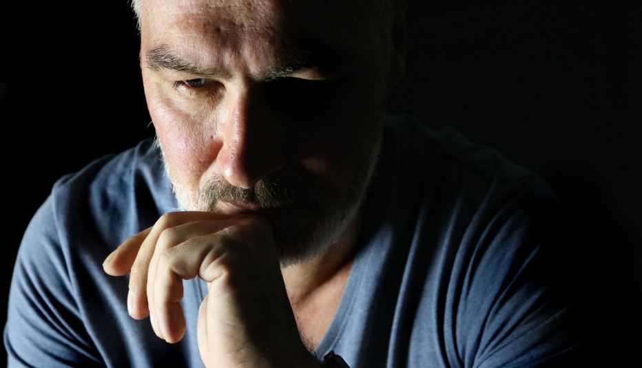 close up of a man looking sad and confused, set against a black background