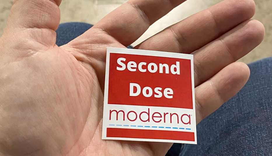 person holing a sticker that says moderna second dose