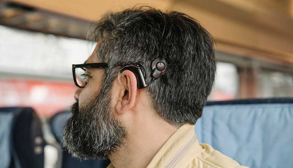 profile of a man wearing a cochlear implant riding on a train