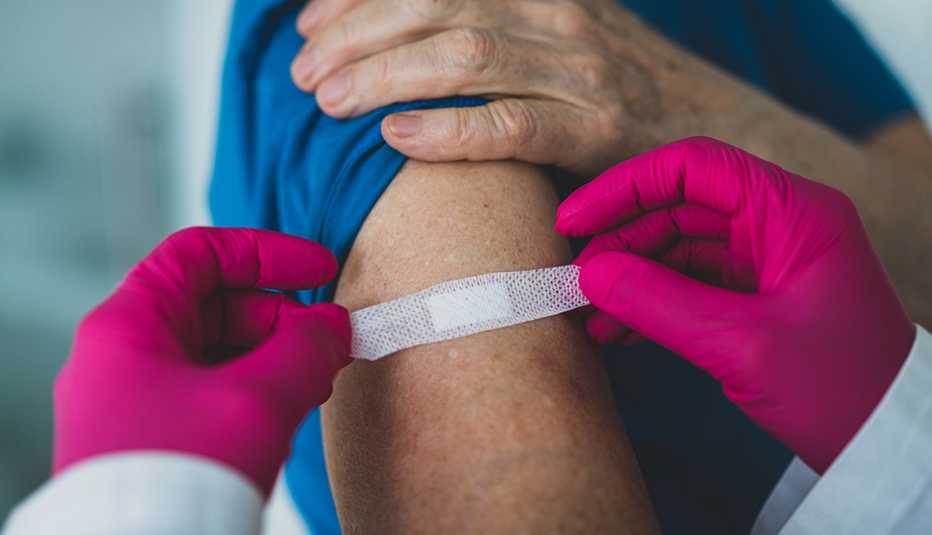 Doctor placing a bandaid on a patient's arm.