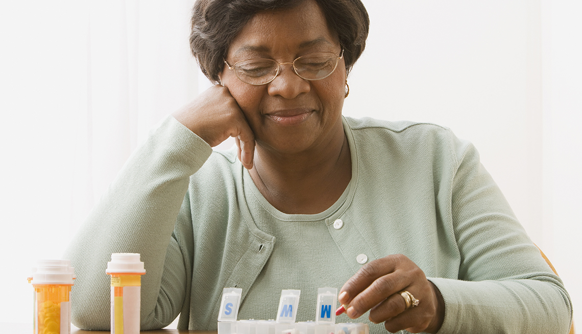 Woman putting her prescription medications in a pill box.