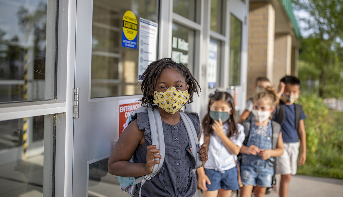 A group of kids stand outside of school with masks on