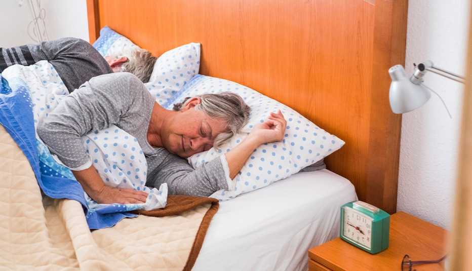 Mature couple sleeping, right before waking up. Woman looks stressed.