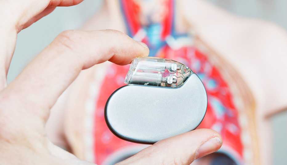 A cardiac pacemaker in front of a plastic model of a human torso