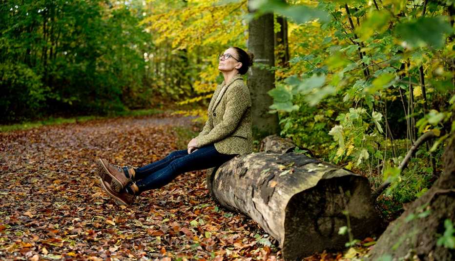 woman sitting on a tree trunk in the wood looking relaxed
