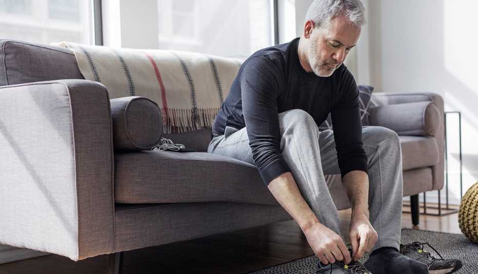 Man sits on couch and ties his sneaker