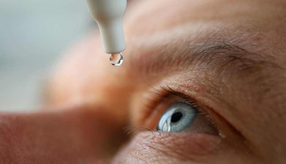 a closeup of a person applying eye drops