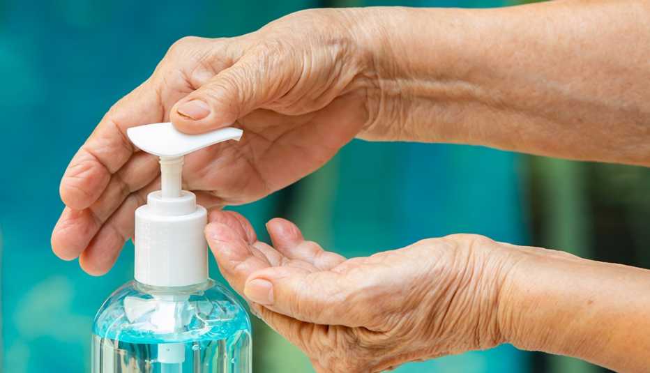 bottle of hand sanitizer showing a womans hands using it by depressing the pump top