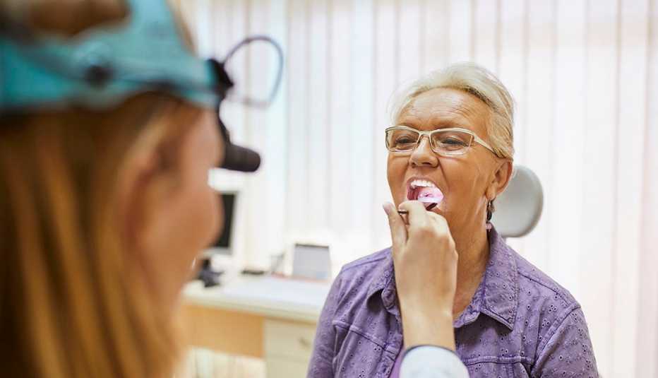 doctor examining female patient's mouth