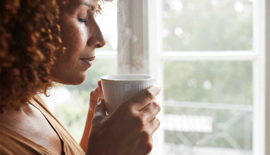 a woman with her eyes closed smelling a cup of coffee