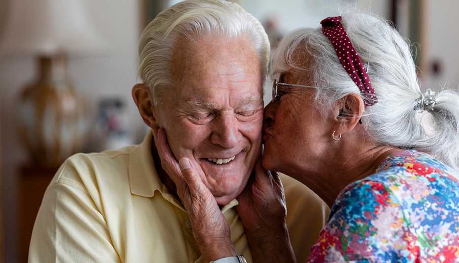 A woman kissing a smiling man on the cheek