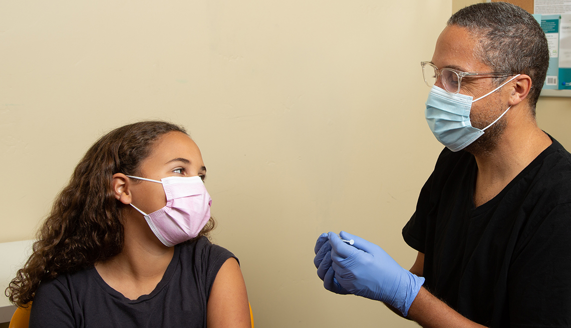 adolescent receiving a COVID vaccination, wearing a mask