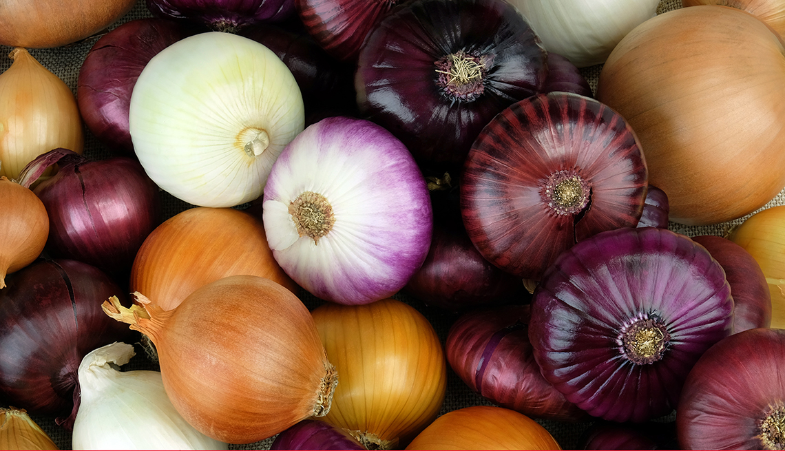 closeup of a bin of yellow white and red onions mixed together