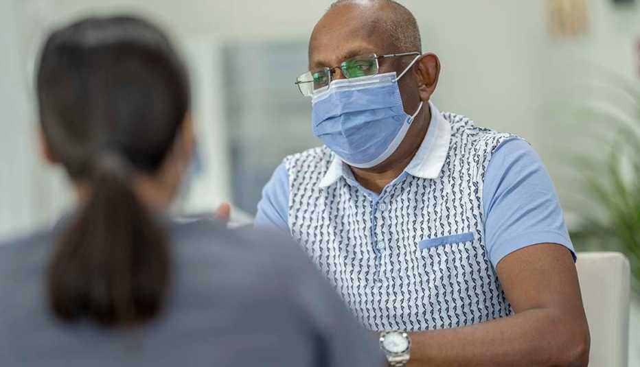 a masked patient speaks with a medical provider