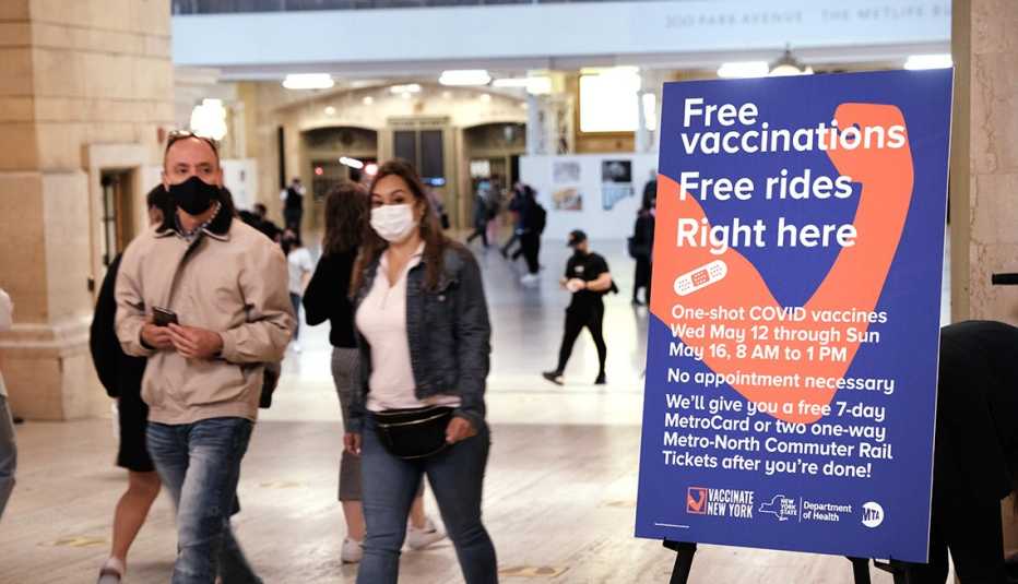People walk through Grand Central Terminal where a pop-up site for COVID-19 vaccinations opened on May 12, 2021 in New York City. A sign reads free vaccinations - free rides.