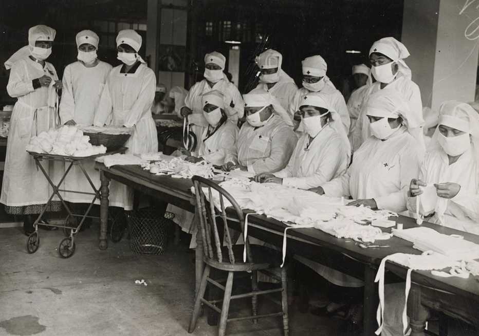 black and white photo from nineteen eighteen showing masked volunteers making anti influenza masks