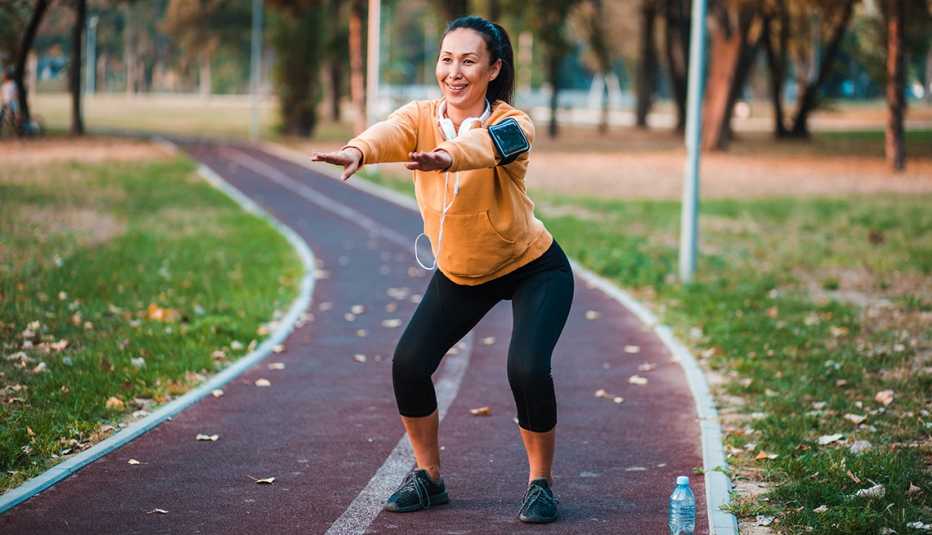 woman standing on a track outdoors performing a squat exercise