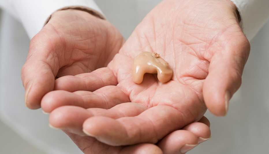 doctor's hands holding hearing aid