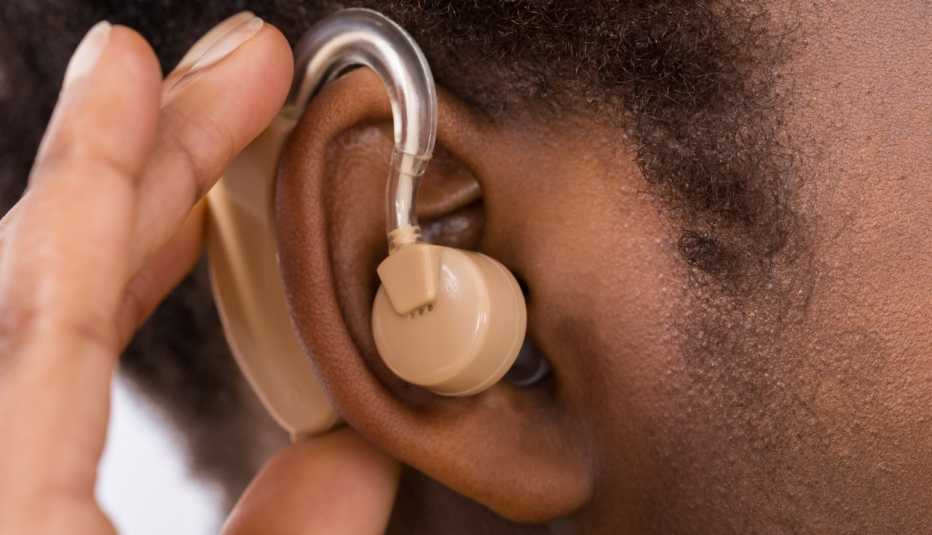 close-up of woman putting in an over-the-counter hearing aid