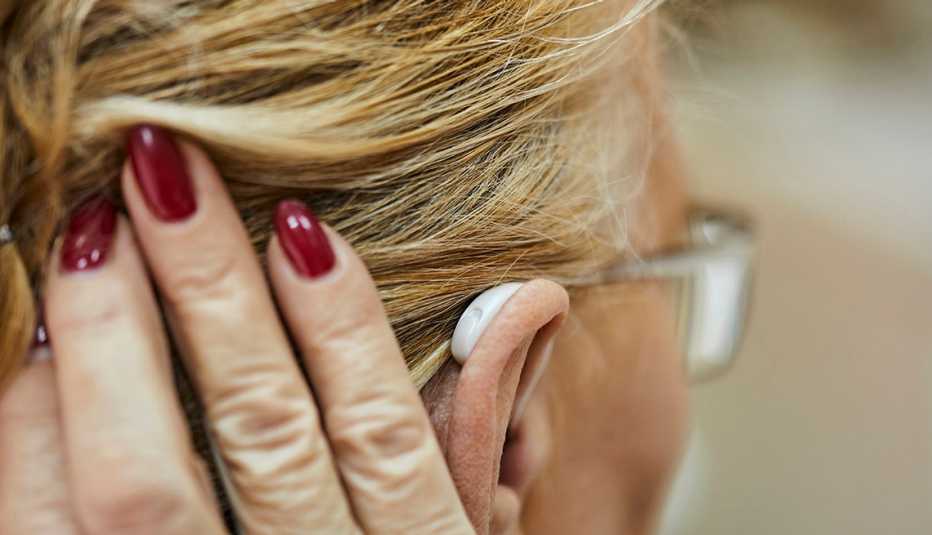 woman holding her hair aside to show her hearing aid