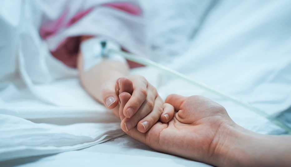 parent holding a child's hand, child is in a hospital bed
