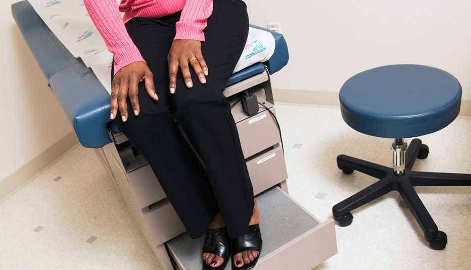 African American woman sitting on an exam table in a doctor's office,
