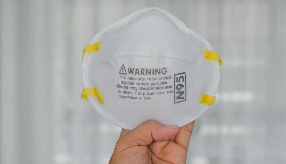 close up of a woman's hand holding an n95 mask