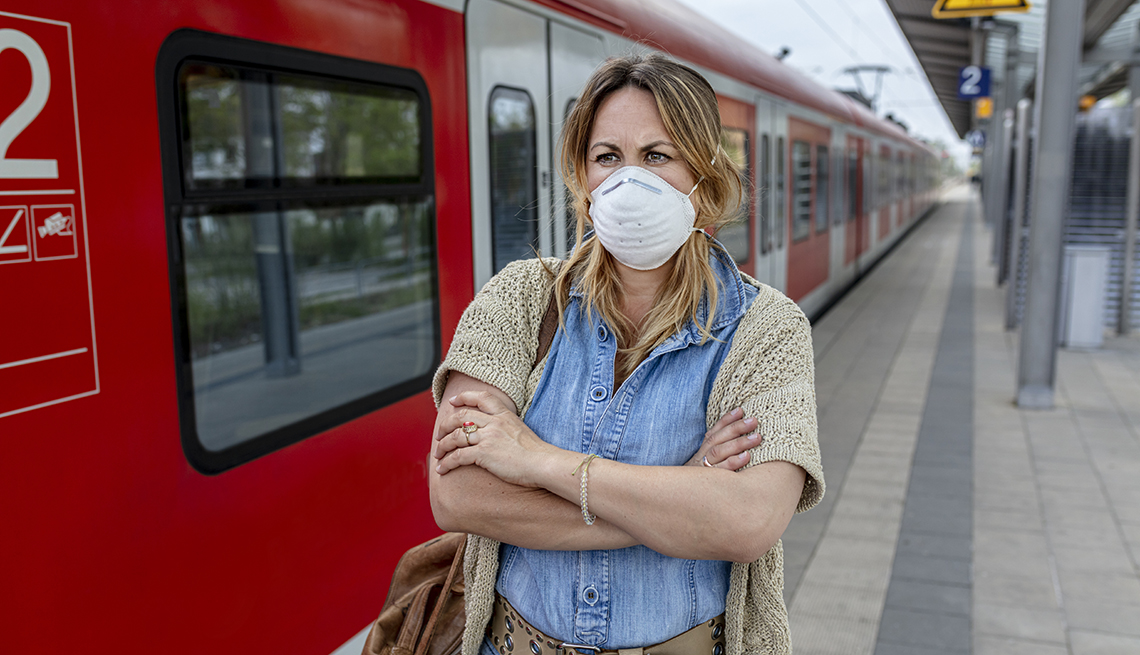 woman standing on a subway platform wearing an N95 face mask