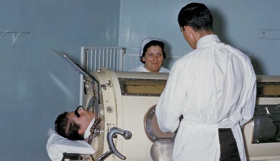 Hospital staff examine a patient in an iron lung.
