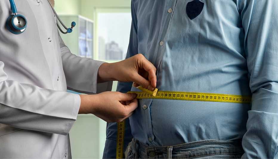 doctor measuring an overweight man's stomach