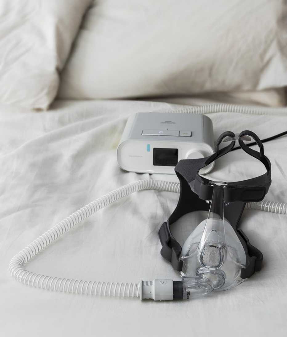 close up of a Philips respironics DreamStation device on a bed, designed to keep airways open during sleep, preventing obstructive sleep apnea