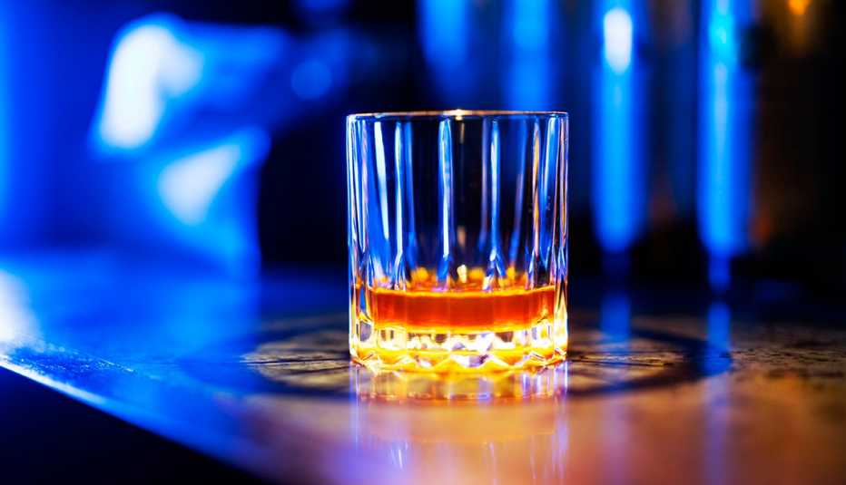 glass of alcohol sitting on a bar, illuminated in blue light